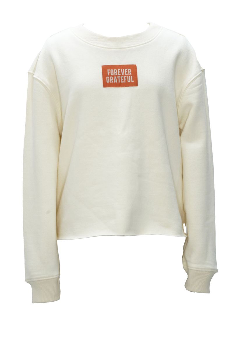 An off-white long-sleeve crewneck sweatshirt featuring a small orange rectangular patch on the chest with the text 'FOREVER GRATEFUL' in white.