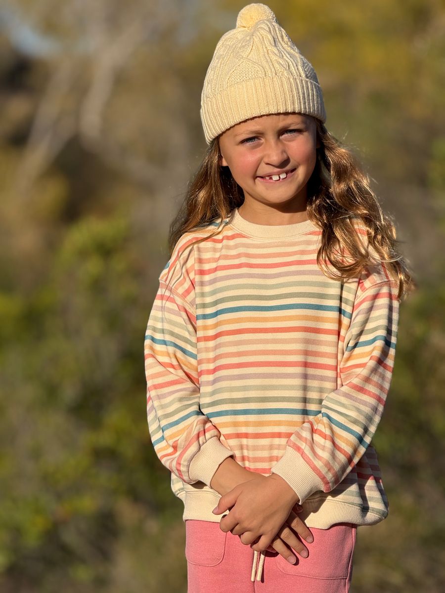 Young girl wearing a striped sweater and cream beanie outdoors
