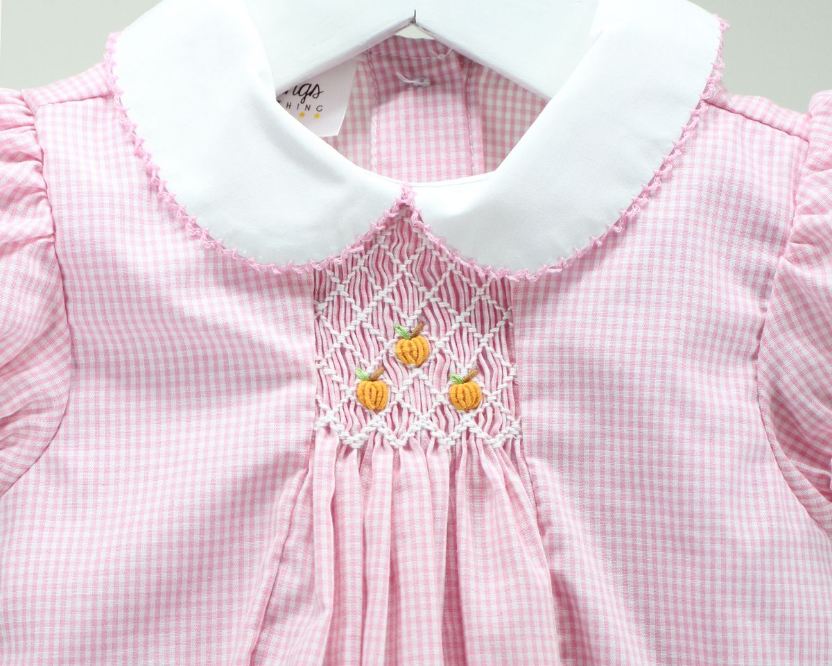 Pink and white gingham dress with a white Peter Pan collar and smocked pumpkin details on the chest.