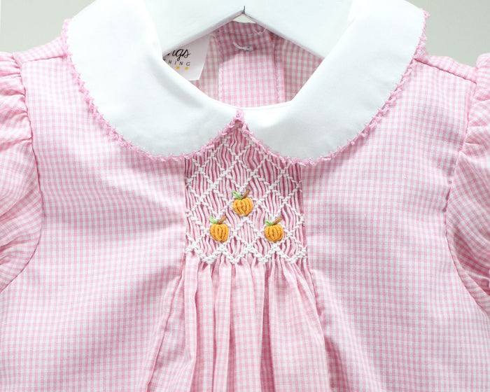Pink and white gingham dress with a white Peter Pan collar and smocked pumpkin details on the chest.