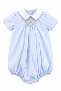 A baby boy's short-sleeve romper in a light blue and white gingham pattern, featuring a white collar with a thin orange trim, smocked detailing at the chest with three small yellow flowers, and elasticated leg cuffs.