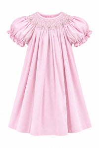 A light pink baby dress with short puffed sleeves and delicate white embroidered detailing around the neckline, hanging on a white hanger against a solid gray background.