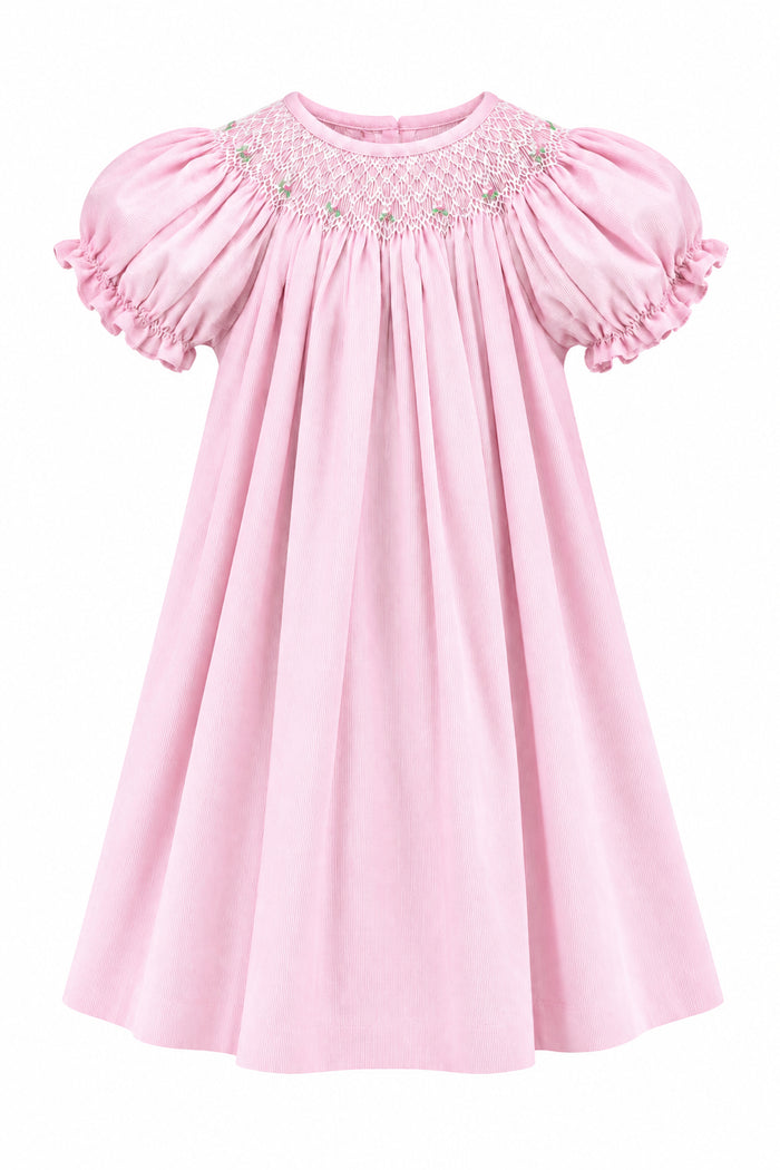 A light pink baby dress with short puffed sleeves and delicate white embroidered detailing around the neckline, hanging on a white hanger against a solid gray background.