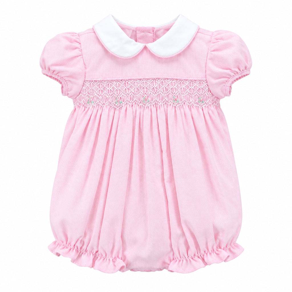 A baby girl's pink bubble romper with a white Peter Pan collar and delicate lace smocking across the chest, hanging on a white hanger against a solid gray background.
