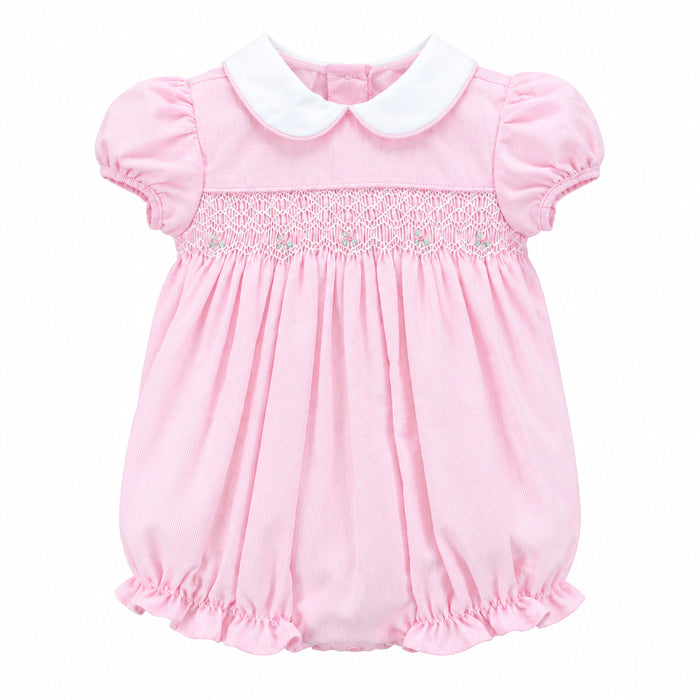 A baby girl's pink bubble romper with a white Peter Pan collar and delicate lace smocking across the chest, hanging on a white hanger against a solid gray background.