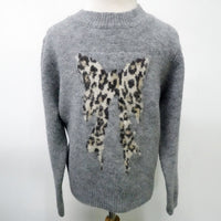A gray knit sweater displayed on a mannequin, featuring a large leopard-print bow motif knitted across the chest.