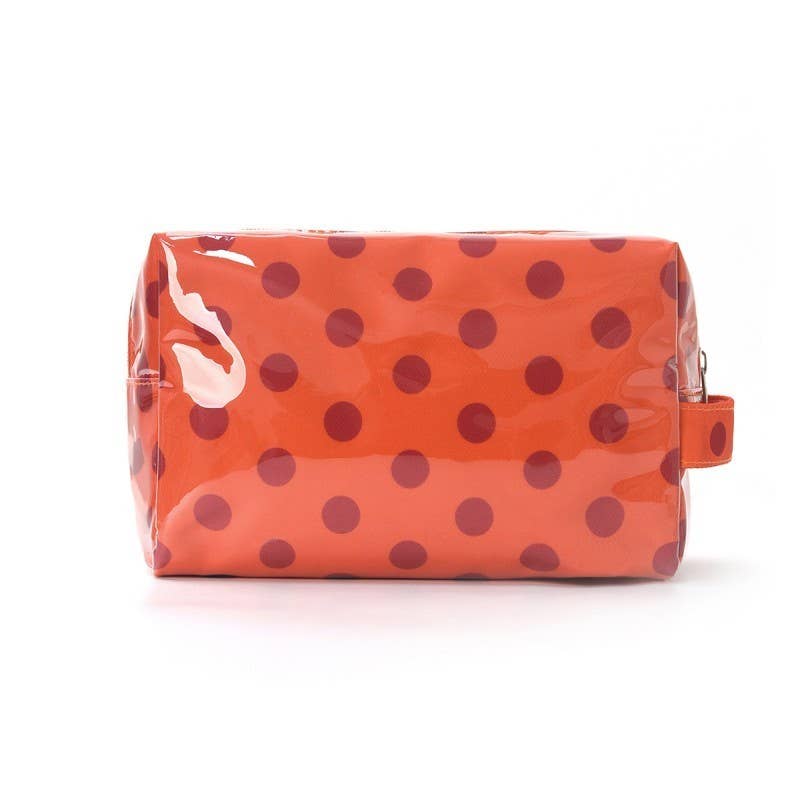 A glossy orange cosmetic pouch with dark red polka dots, shown on a clean white background.