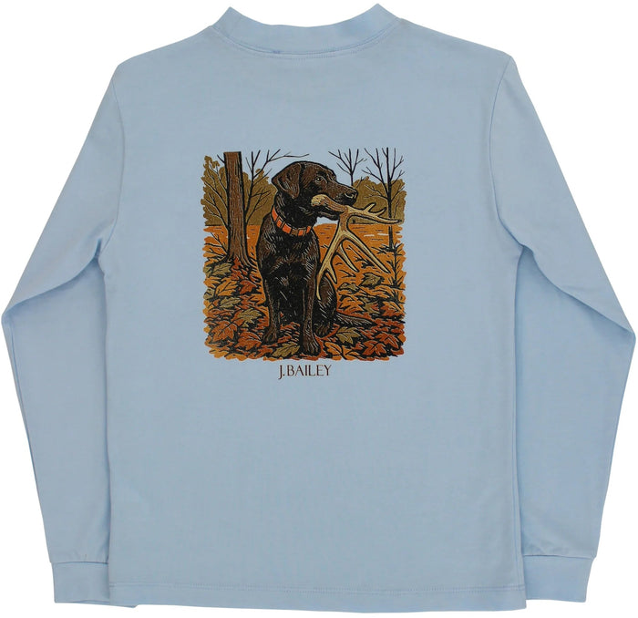 A light blue long-sleeve t-shirt with a graphic print of a black Labrador retriever holding a duck in its beak, standing in an autumn forest. The text 'J.