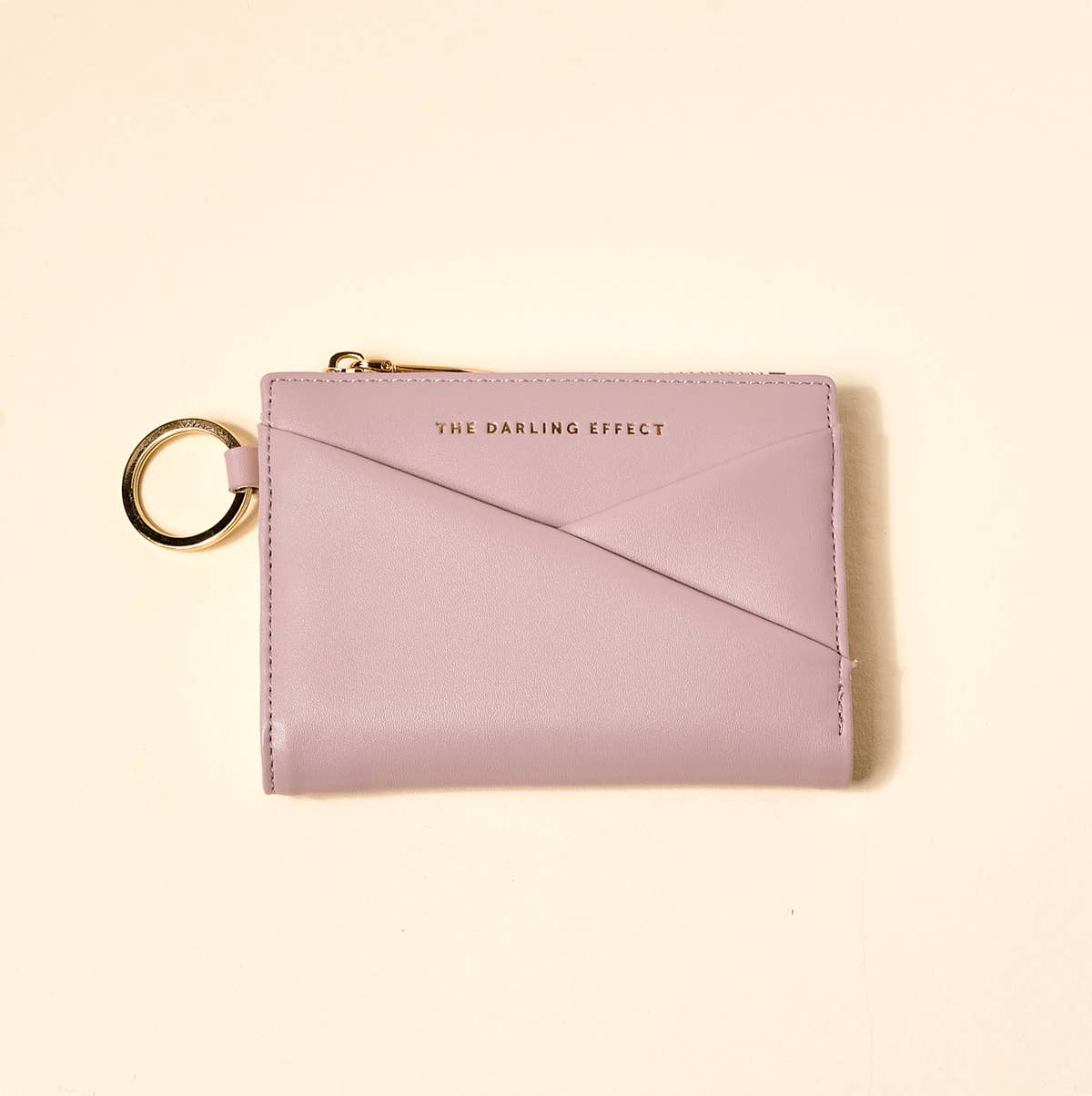 Pink wallet with keychain on a beige background