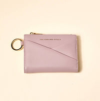 Pink wallet with keychain on a beige background