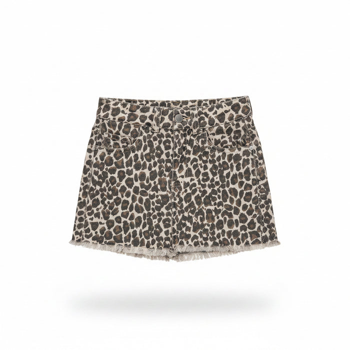 A leopard print denim mini skirt with a frayed hem, held up on a clear plastic hanger by a hand with blue nail polish in a retail store setting.