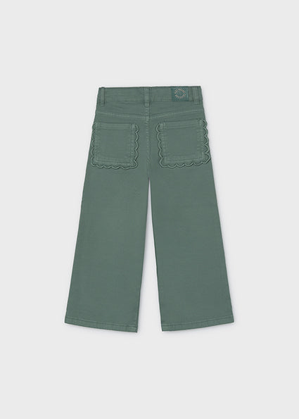 A pair of muted sage green wide-leg pants shown from the back, featuring decorative scalloped stitching around the two back pockets, on a light gray background.