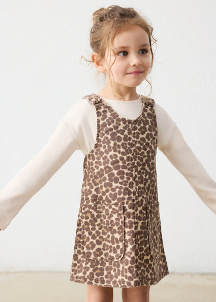 Young girl wearing a leopard print dress against a plain background