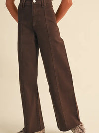 A person wearing dark brown wide-leg jeans with a high waist, shown from the waist down against a plain beige studio background.