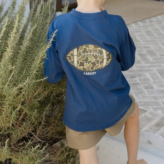 Person wearing a blue t-shirt with a football design outdoors