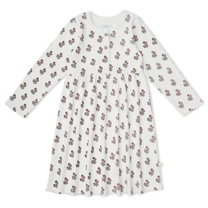 A long-sleeve baby dress in white with an all-over small brown and pink floral print, featuring a buttoned neckline and a gathered skirt.