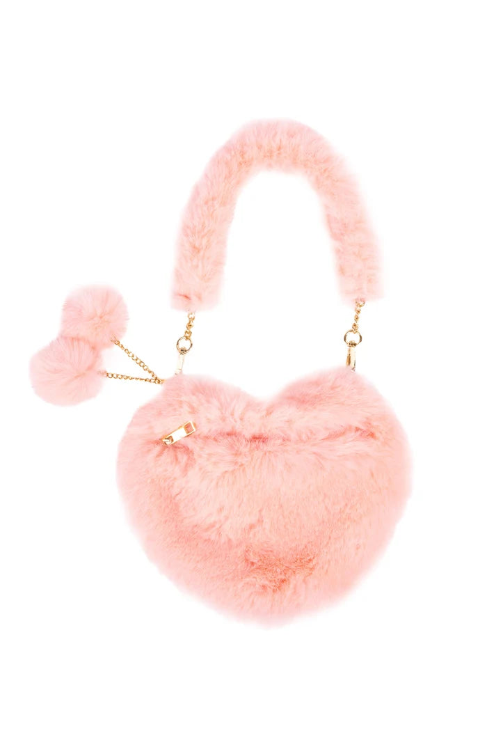 A light pink fluffy faux-fur handbag with a matching curved handle, gold-tone chain details, and two small pom-poms on the side, shown on a plain white background.