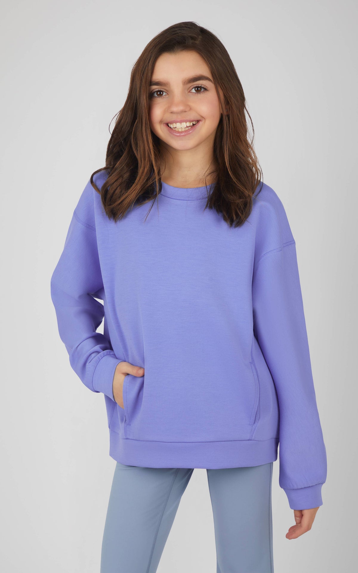Young girl wearing a purple sweatshirt and pants on a white background