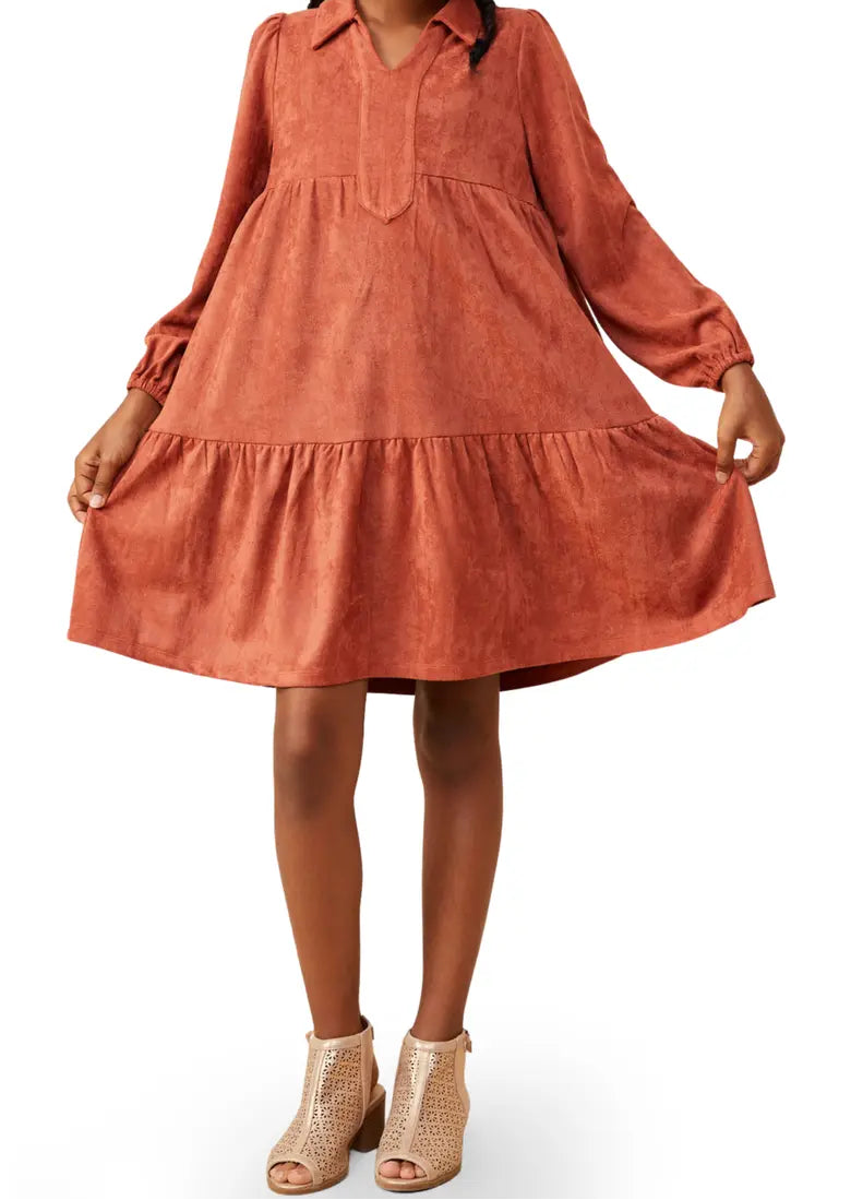 A Girl wearing a terracotta-colored long-sleeve tiered dress with a collared neckline, paired with beige ankle boots, against a plain white background.