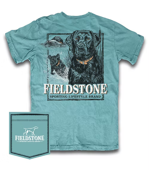 A light teal graphic t-shirt featuring a large print of a black dog with a hunting dog and a duck in the background, with the text 'FIELDSTONE SPORTING LIFESTYLE BRAND'. A matching fabric pocket patch is shown in the bottom-left corner.