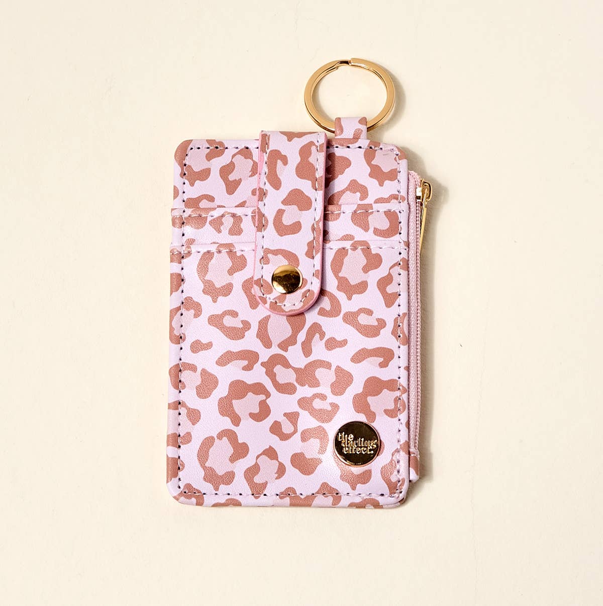 Pink leopard print pouch with gold accents on a beige background