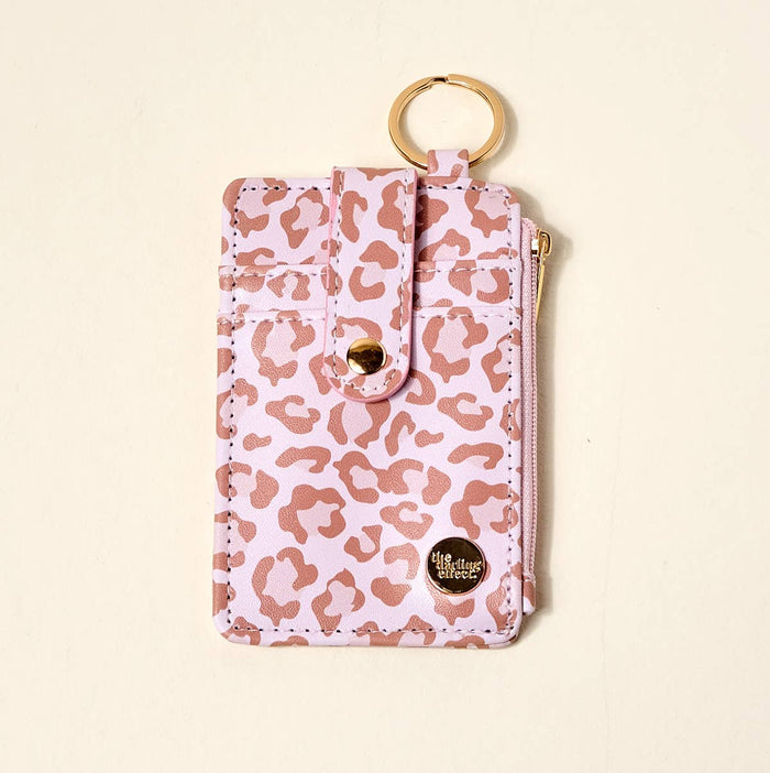Pink leopard print pouch with gold accents on a beige background