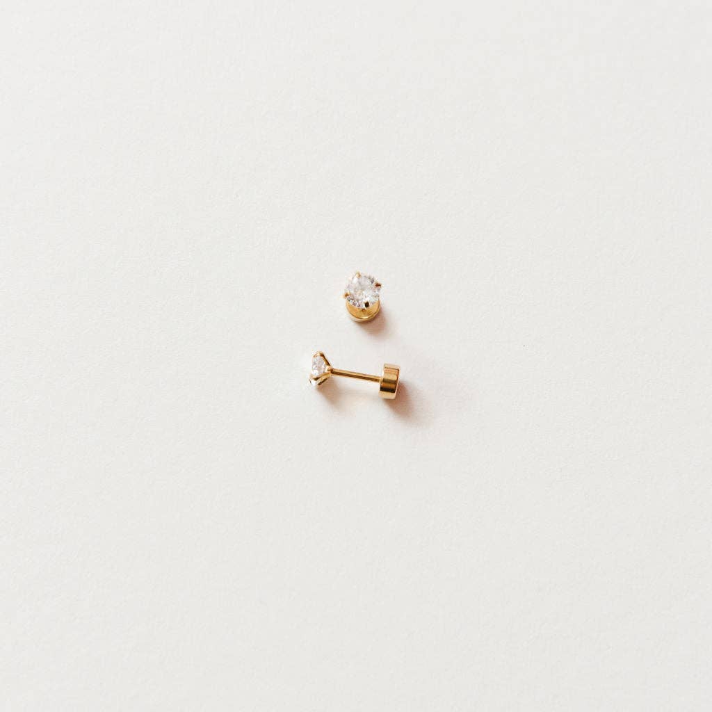 Two gold earrings on a light gray background