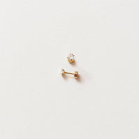 Two gold earrings on a light gray background
