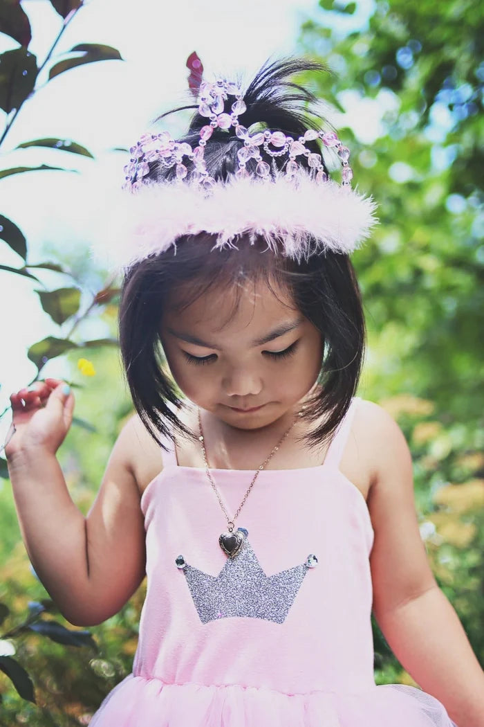 Young girl in a pink dress with a tiara outdoors