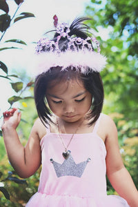 Young girl in a pink dress with a tiara outdoors