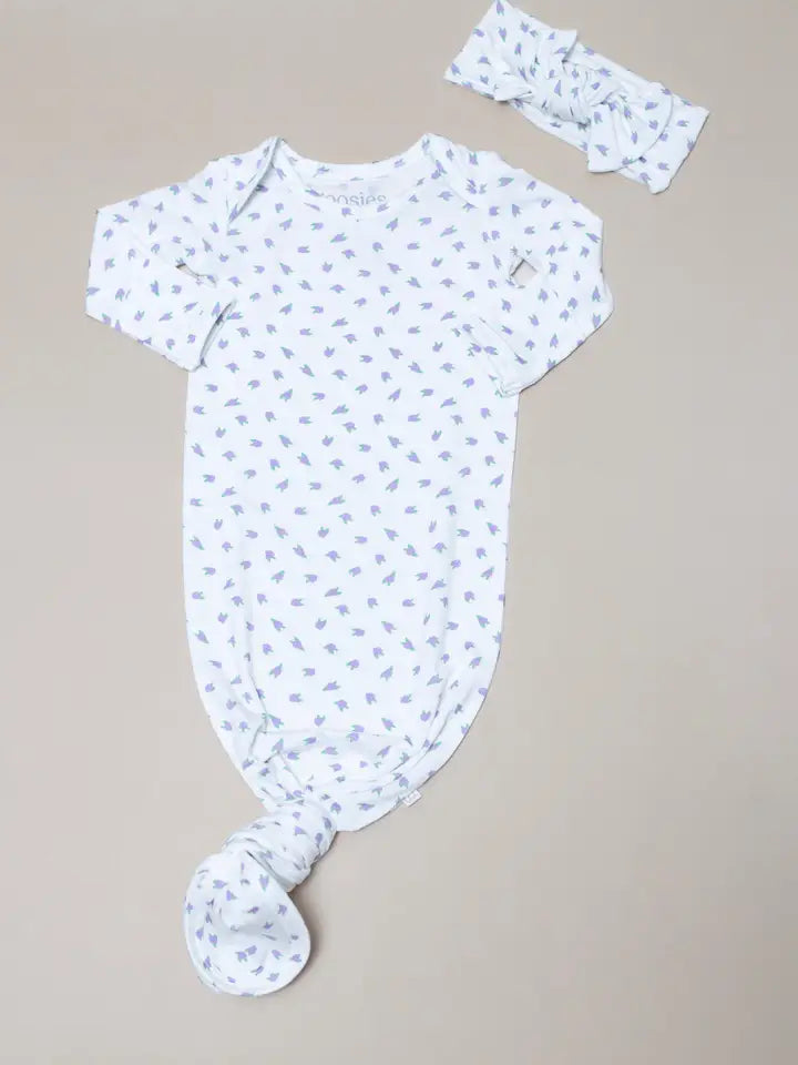 A baby outfit set featuring a short-sleeve knotted bodysuit and a matching headband, both in white with a light blue leaf print, laid flat on a neutral beige background.