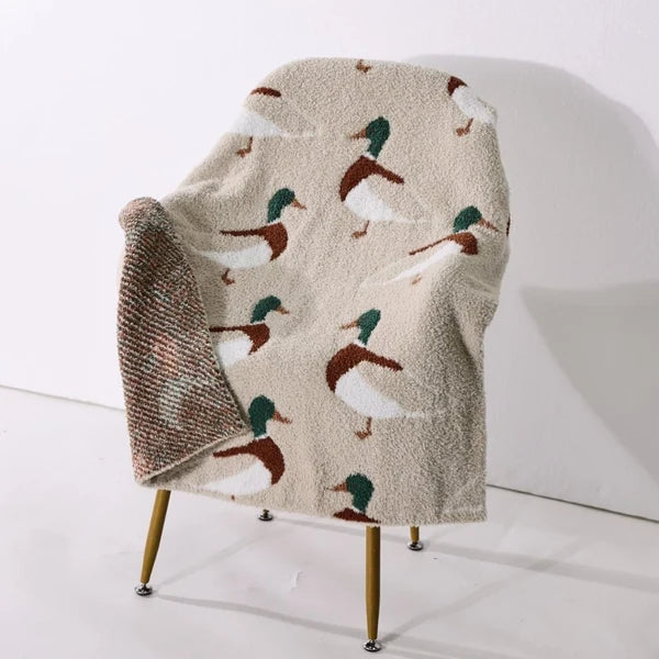 Blanket with duck pattern draped over a chair on a white background