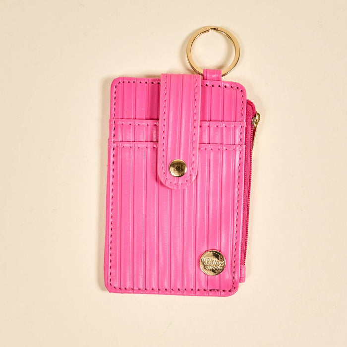 Pink cardholder with gold accents on a beige background