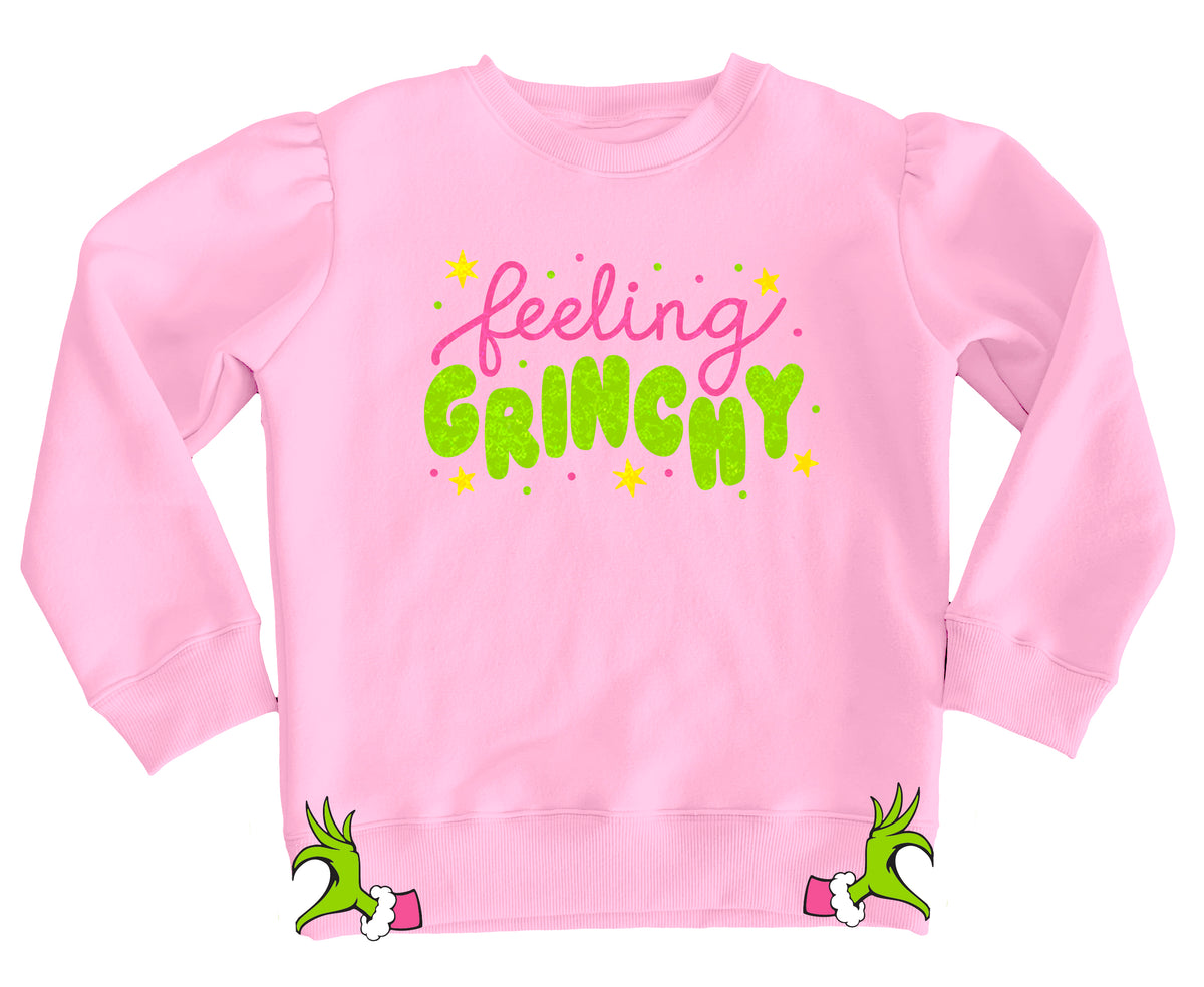 Pink sweatshirt with 'feeling Grinchy' text and Grinch hands on a white background