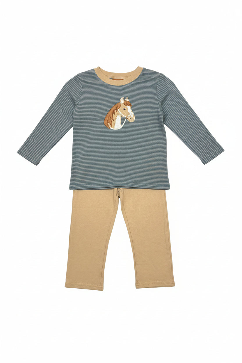 A children's two-piece pajama set hanging on a clear hanger in a retail store. The set includes a long-sleeve top with a blue and beige micro-check pattern, a tan crew neck, and a brown and white horse graphic on the chest, paired with tan pants.