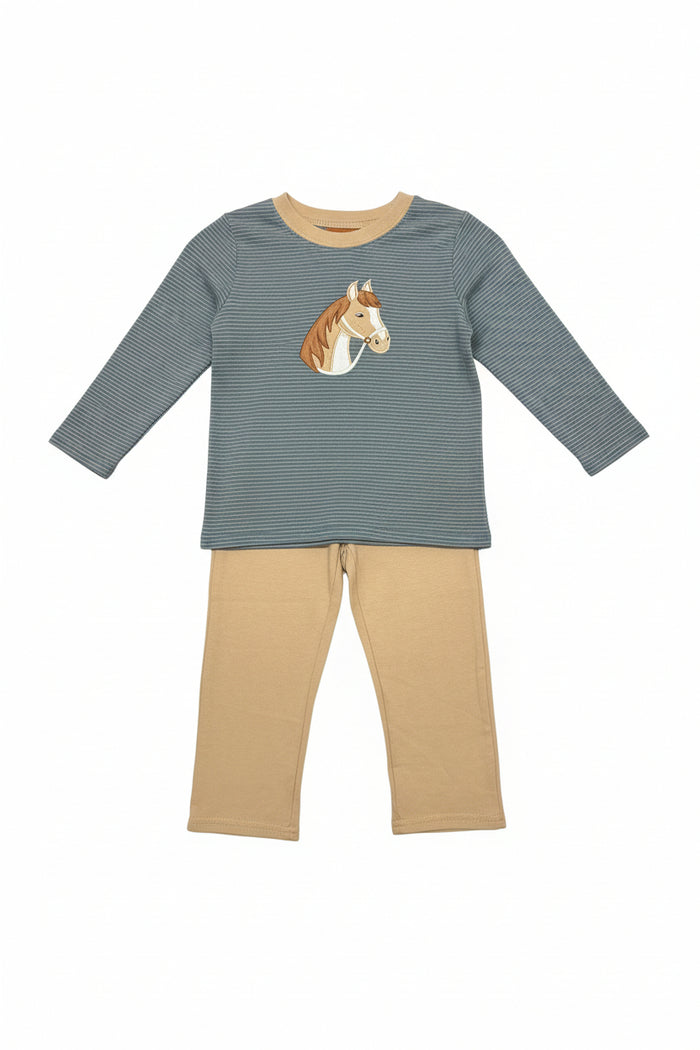 A children's two-piece pajama set hanging on a clear hanger in a retail store. The set includes a long-sleeve top with a blue and beige micro-check pattern, a tan crew neck, and a brown and white horse graphic on the chest, paired with tan pants.