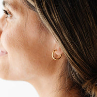 Close-up of a woman wearing a gold hoop earring.