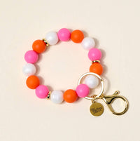 Colorful beaded bracelet with a gold clasp and keychain on a beige background