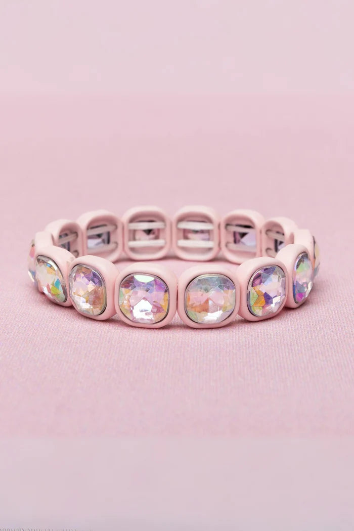 A light pink silicone bracelet featuring round, faceted iridescent clear rhinestones in a matching pink bezel setting, displayed on a soft pink textured background.