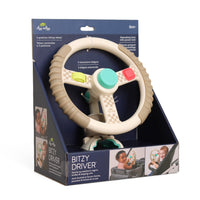 A baby toy steering wheel activity tray by Bitzy Drivers, shown inside its retail packaging display. The toy features a beige and white checkered pattern, a central mint green button, a red stop button, and colorful push buttons in yellow and green.