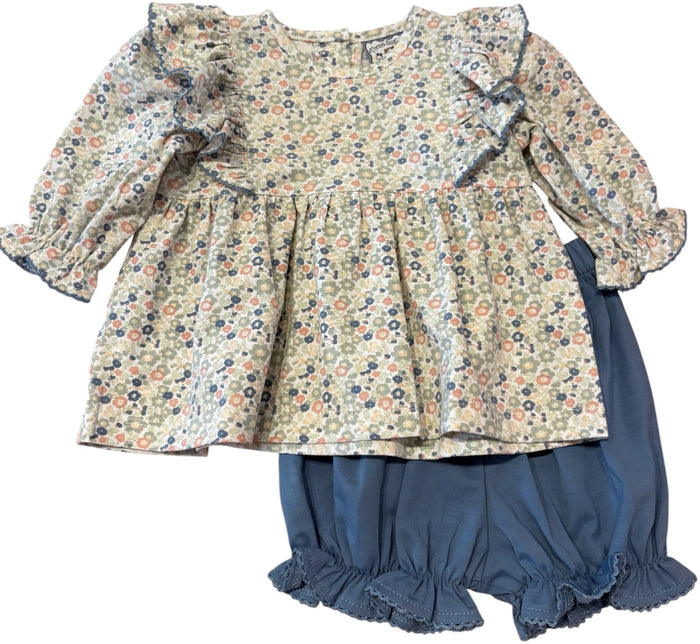 A toddler girl's two-piece outfit featuring a long-sleeve ruffled blouse with a small multicolor floral print on a cream background, paired with navy blue ruffled bloomers, shown flat on a white background.
