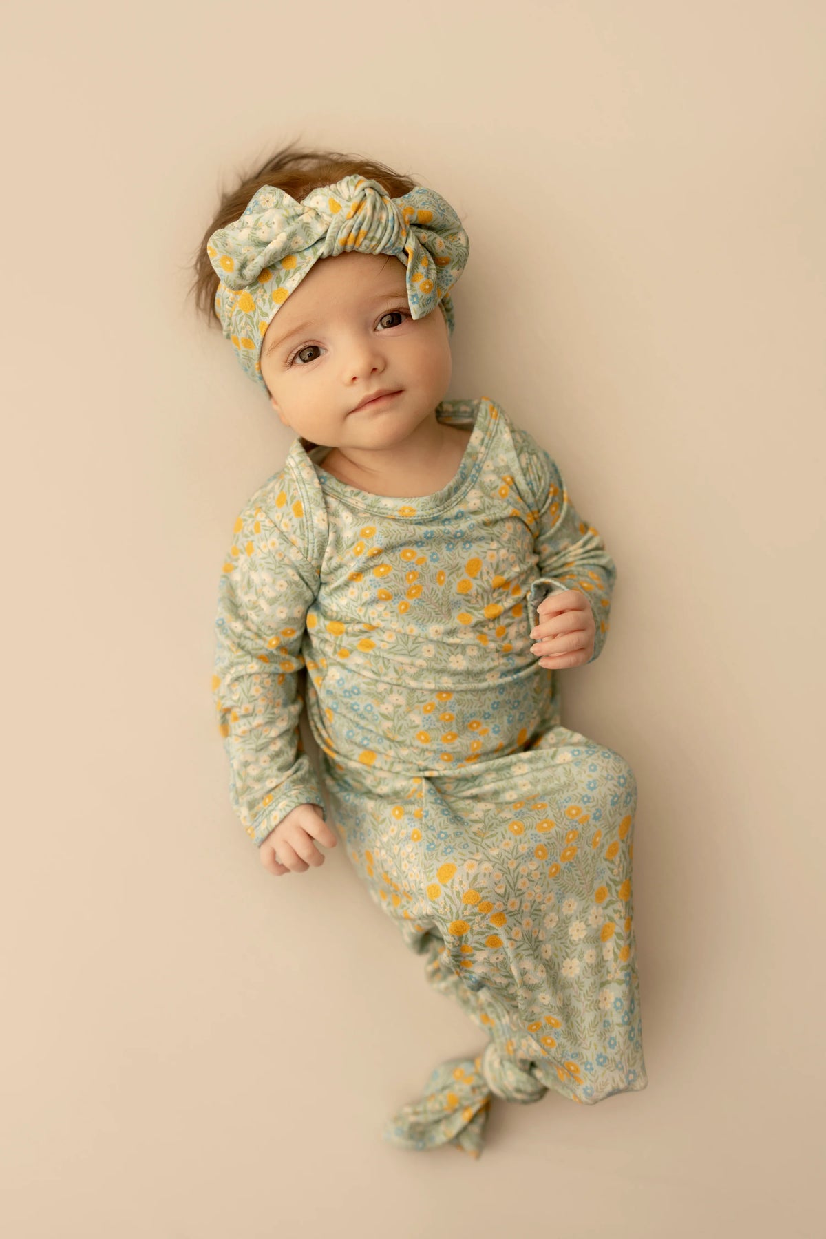 Baby in floral outfit and headband on a beige background