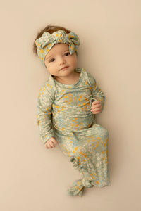 Baby in floral outfit and headband on a beige background