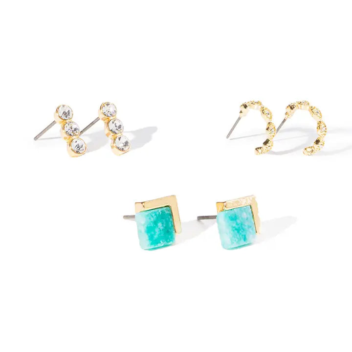 Three pairs of gold-toned stud earrings on a white background: two small clusters with clear stones and one pair with square turquoise-blue stone centers and gold borders.