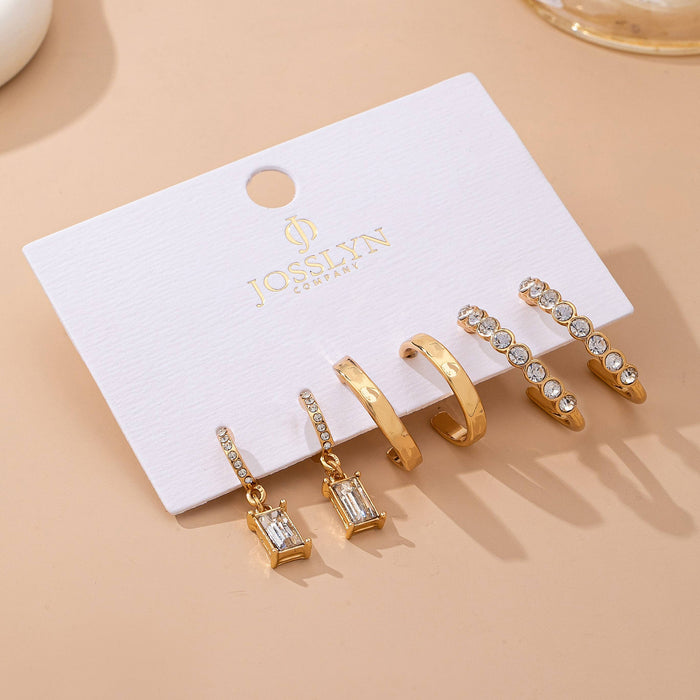 Set of gold earrings on a JOSEPHINE branded card against a beige background