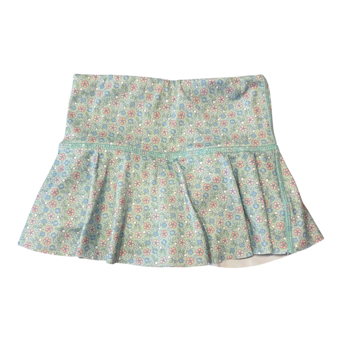 A women's tennis skirt with a ruffled hem and a wide waistband, featuring a light blue-green base with a dense multicolor floral and medallion pattern in pink, red, and yellow.