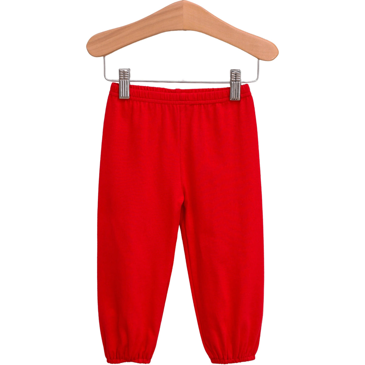 Bright red jogger pants for kids, hanging from a wooden hanger with metal clips against a plain white background.