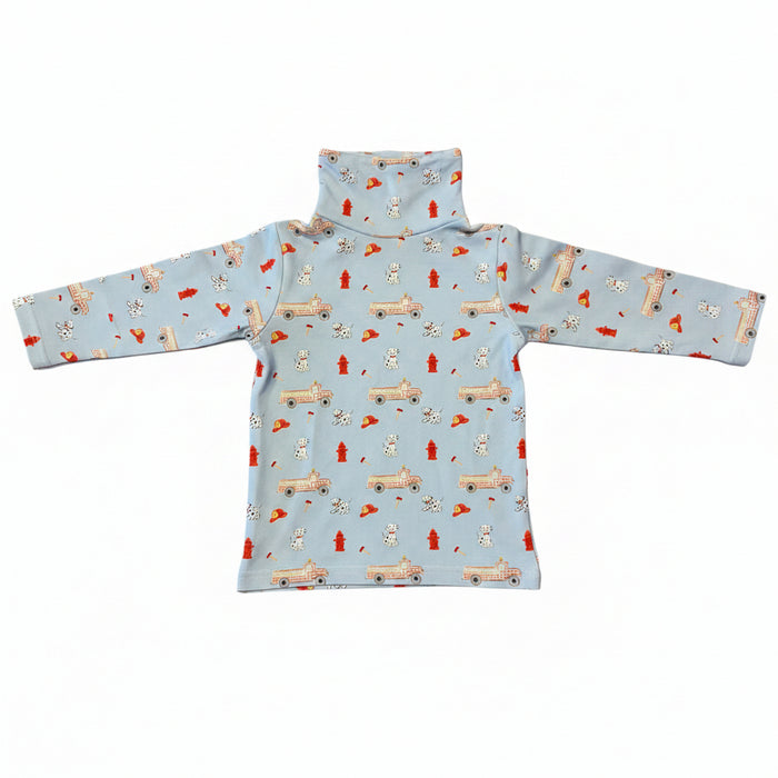 A light blue long-sleeve turtleneck top with a repeating pattern of fire trucks, Dalmatian dogs, and red fire hydrants, laid flat on a white background.