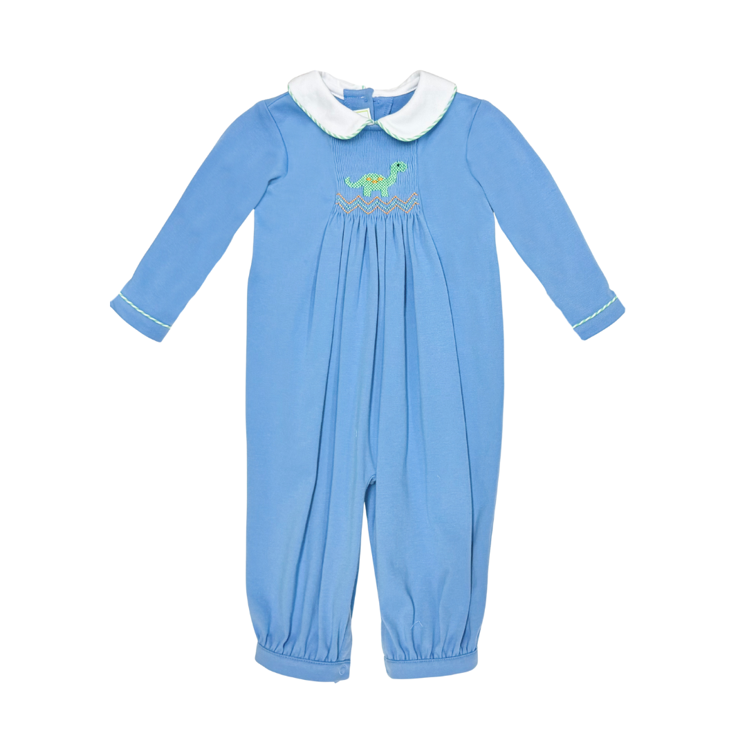 A baby's long-sleeve footless jumpsuit in light blue, featuring a white faux-fur Peter Pan collar, white piping on the cuffs, and a smocked chest design with a green dinosaur and gold pattern.