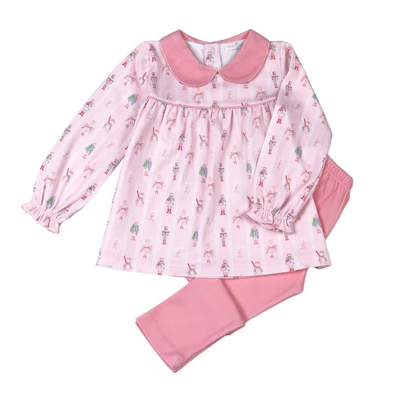 A two-piece girls' pajama set featuring a long-sleeve top with a pink Peter Pan collar and an all-over nutcracker print, paired with solid pink pants, shown on a plain white background.
